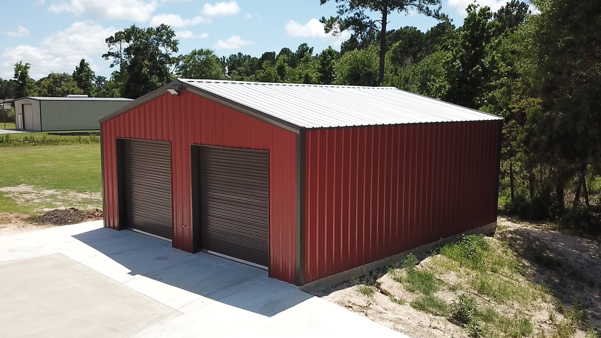 Red prefab metal building kit with roll-up doors on concrete slab — pole barn and steel building kits serving Atlanta GA