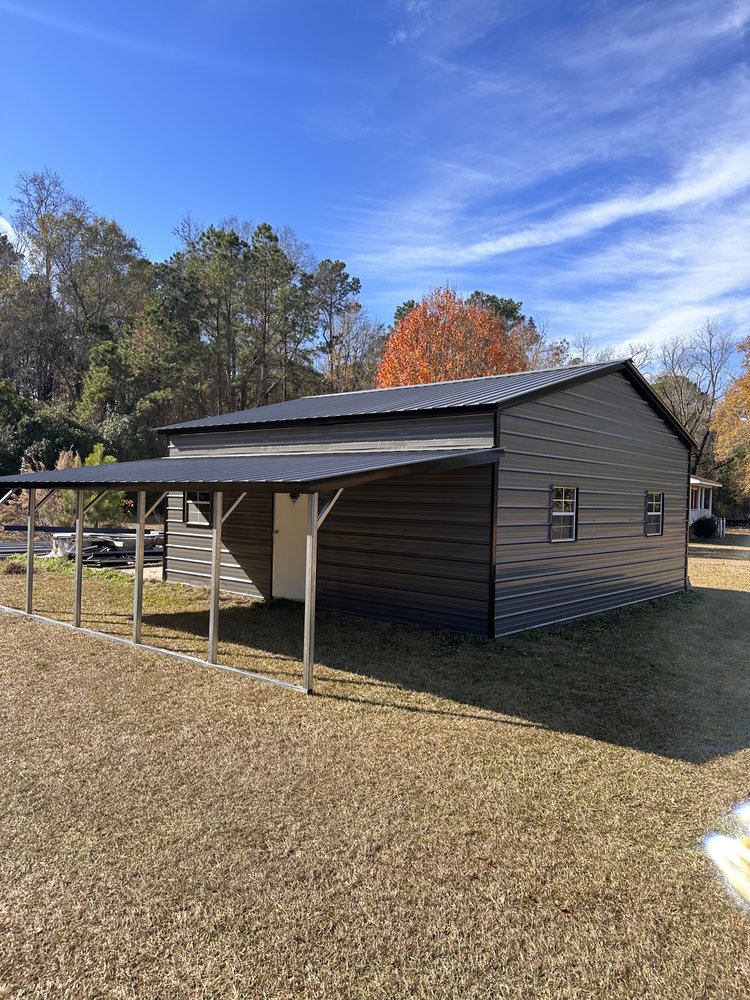 Gray metal building with lean-to carport on grassy lot in autumn — ready for fall storms in NC